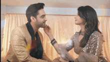 a man and a woman are looking at each other in a room . the woman is touching the man 's face .