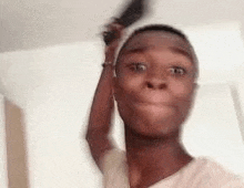 a young man is brushing his hair with a comb while making a funny face .