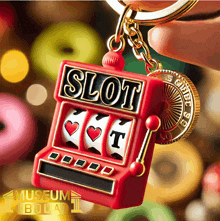 a red slot machine keychain is being held by a hand