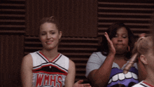 two cheerleaders are wearing wmhs uniforms and one is giving a high five