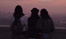 three women are standing on a balcony looking out over a city
