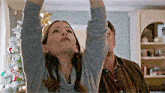 a man and a woman are looking up at the ceiling in a living room .