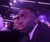 a man in a suit and tie is making a funny face in a crowd .