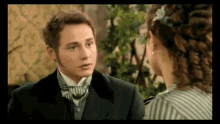 a man in a suit and tie is talking to a woman in a striped dress .