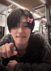 a person with a pink bow on their forehead pointing at the camera