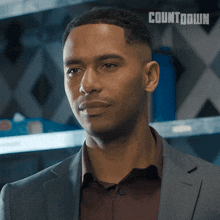 a man in a suit stands in front of a wall that says countdown