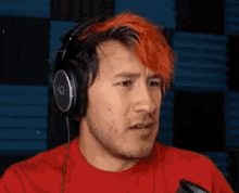 a man with red hair and headphones is making a funny face .