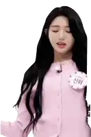 a woman with long black hair is wearing a pink sweater with a name tag on it .