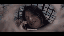 a woman is laying in a cage and talking on a cell phone