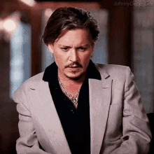 johnny depp is wearing a suit and a black shirt and a necklace .