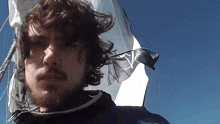 a man with a beard is standing in front of a flag with the letter vp on it
