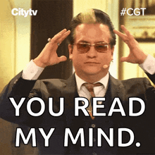 a man in a suit and tie holds his hands to his head with the words you read my mind below him