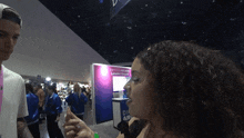 a woman talks to a man in front of a sign that says ' defense rising leader board '
