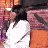 a woman is sitting on a couch with a microphone in front of her