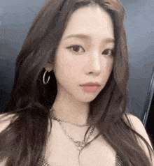 a woman wearing a necklace and hoop earrings is taking a picture of herself .