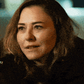 a close up of a woman 's face with a black jacket and sweater on