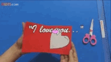 a person holding a piece of paper that says i love you