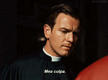 a priest says mea culpa in front of a red shirt