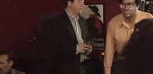 two men are standing next to each other in front of a red wall .