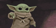 a green baby yoda with a crescent moon necklace around his neck