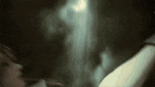 a blurry picture of a person in a dark room with a light coming through the window