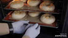 a person is taking a tray of doughnuts out of an oven .