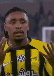 a man wearing a black and yellow striped shirt with a vw logo on it
