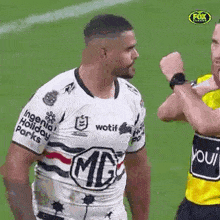 a man in a rugby jersey is standing on a field with another man .