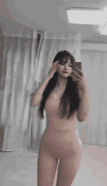 a woman is taking a selfie in front of a mirror in a room .