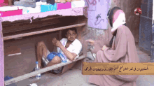 a man sits on a bench next to a woman with arabic writing on a sign