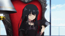 a girl in a black dress is holding a fan