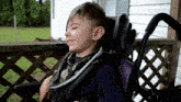 a young boy in a wheelchair with a purple back
