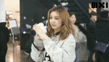 a woman in a grey hoodie is holding a camera in her hand .