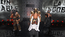 three wrestlers are standing in front of a sign that says un able la la gob