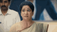 a woman in a sari is making a funny face in front of a man in a white shirt .