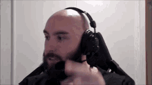 a bald man with a beard is wearing headphones while sitting in a chair .