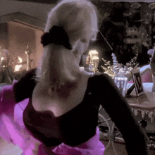 a woman in a pink and black dress is standing in a room