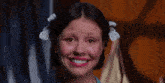 a girl with pigtails is smiling with a tear running down her cheek .