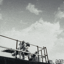 a black and white photo of a person sitting on a railing with the letters ms on the bottom