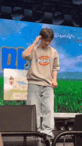 a man wearing a dickies sweatshirt is standing on stage