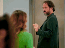 a man in a suit stands in front of a woman in a green dress