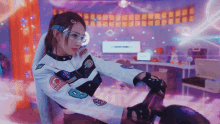 a woman wearing a nasa jacket and glasses is riding a motorcycle