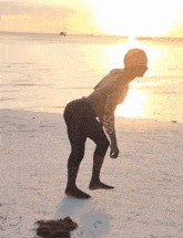 a man with a tattoo on his arm stands on the beach