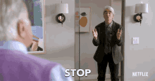 a man in a suit is standing in front of a mirror with the word stop on it