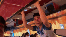 a man hanging from the ceiling of a bus with the letter t on his shirt