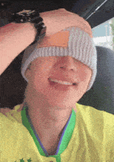 a man wearing a yellow shirt and a gray beanie is smiling