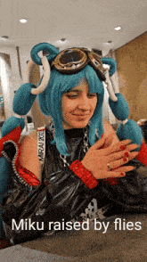 a woman in a blue wig and goggles with the caption " miku raised by flies "