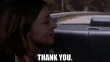 a woman is standing next to a car and saying thank you .