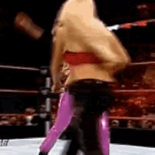 a woman in a red top and pink pants is in a wrestling ring .