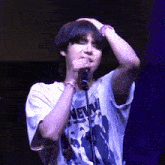 a young man is singing into a microphone while wearing a t-shirt that says new